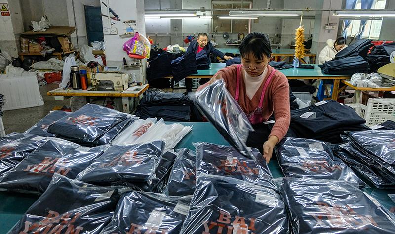 12月4日,来自政和县的村民杨珊在石狮一家服装加工厂车间包装西裤.
